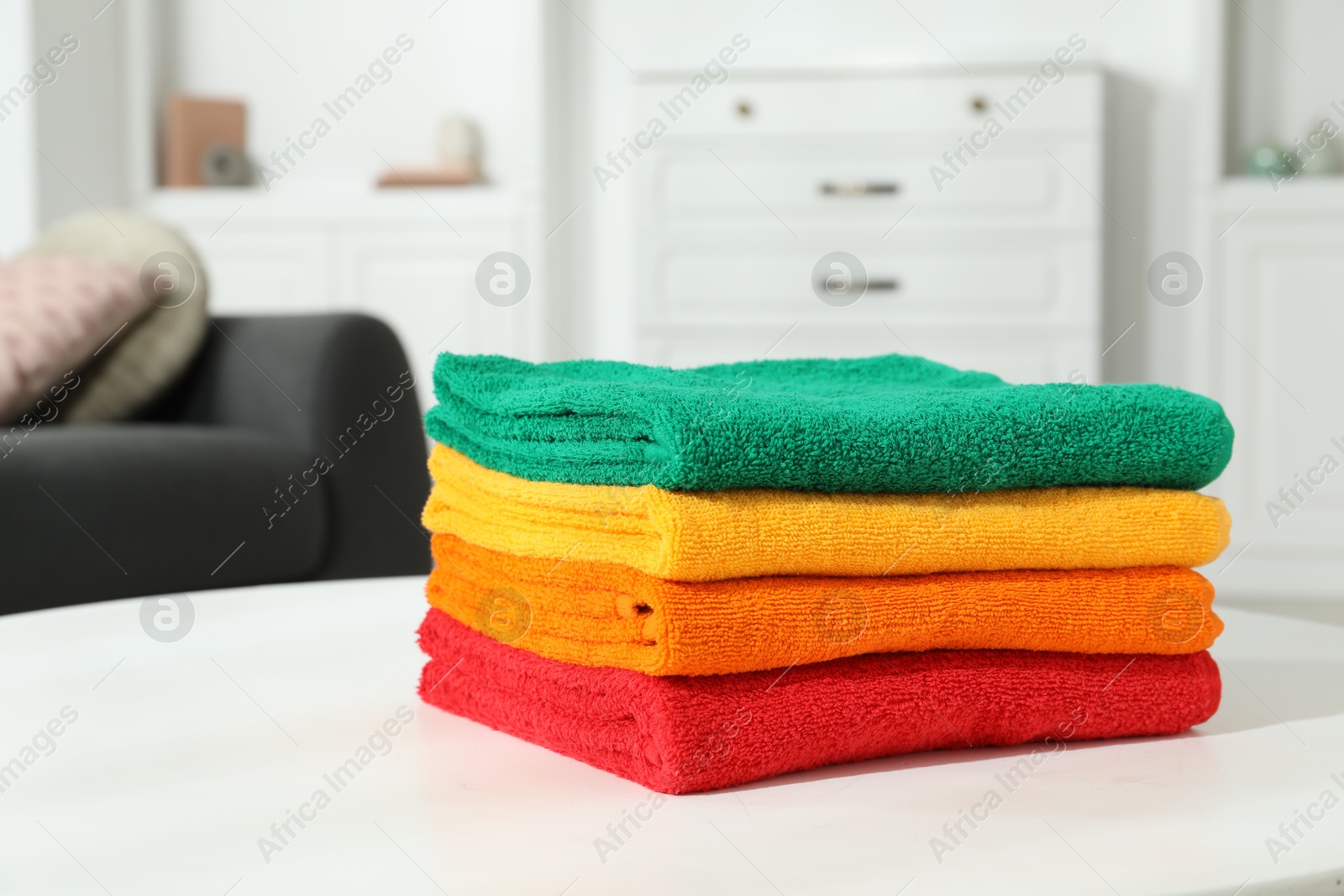 Photo of Fresh colorful terry towels on white table at home, closeup