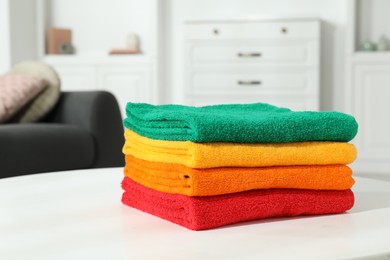 Photo of Fresh colorful terry towels on white table at home, closeup