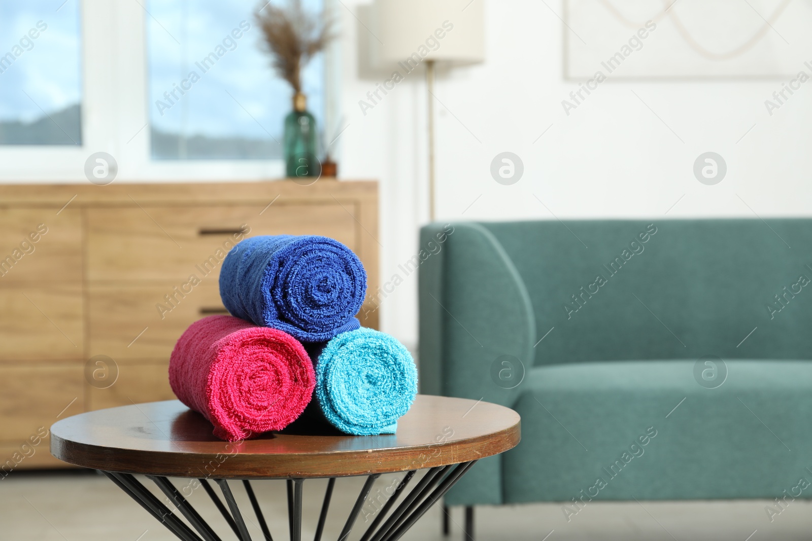 Photo of Fresh colorful terry towels on wooden table at home. Space for text