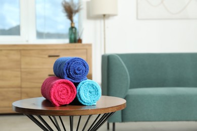 Photo of Fresh colorful terry towels on wooden table at home. Space for text