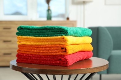 Photo of Fresh colorful terry towels on wooden table at home, closeup