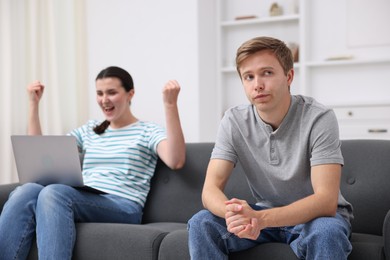 Photo of Man feeling jealous of woman's success at home, selective focus