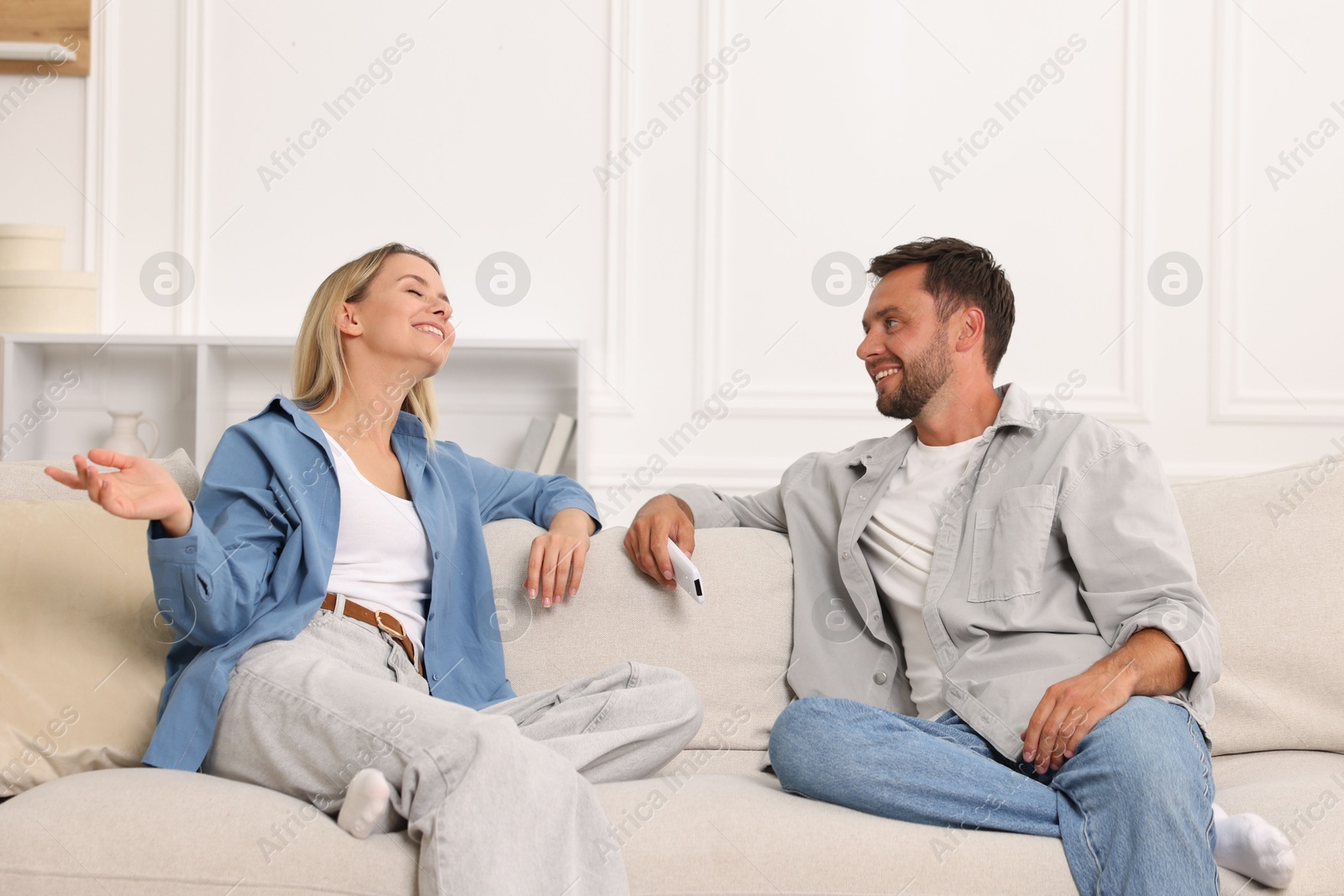 Couple with air conditioner remote control on sofa at home Photo of Couple with air conditioner remote control on sofa at home