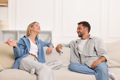 Photo of Couple with air conditioner remote control on sofa at home
