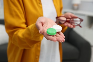 Photo of Woman choosing between glasses and contact lenses indoors, closeup