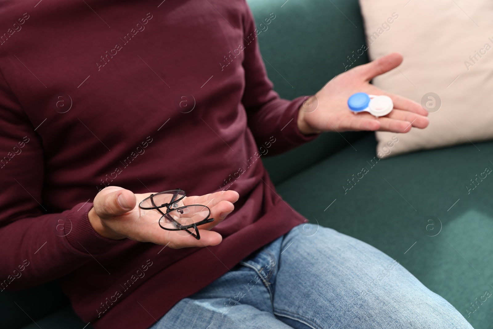 Man choosing between glasses and contact lenses on sofa indoors, closeup Photo of Man choosing between glasses and contact lenses on sofa indoors, closeup