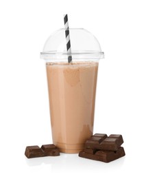 Photo of Tasty milkshake in plastic cup and chocolate pieces isolated on white