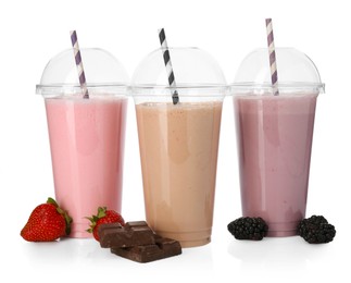 Photo of Milkshakes of different flavors in plastic cups and ingredients isolated on white