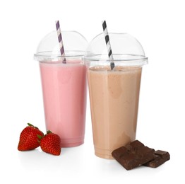 Photo of Milkshakes of different flavors in plastic cups and ingredients isolated on white
