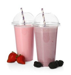 Photo of Milkshakes of different flavors in plastic cups and ingredients isolated on white