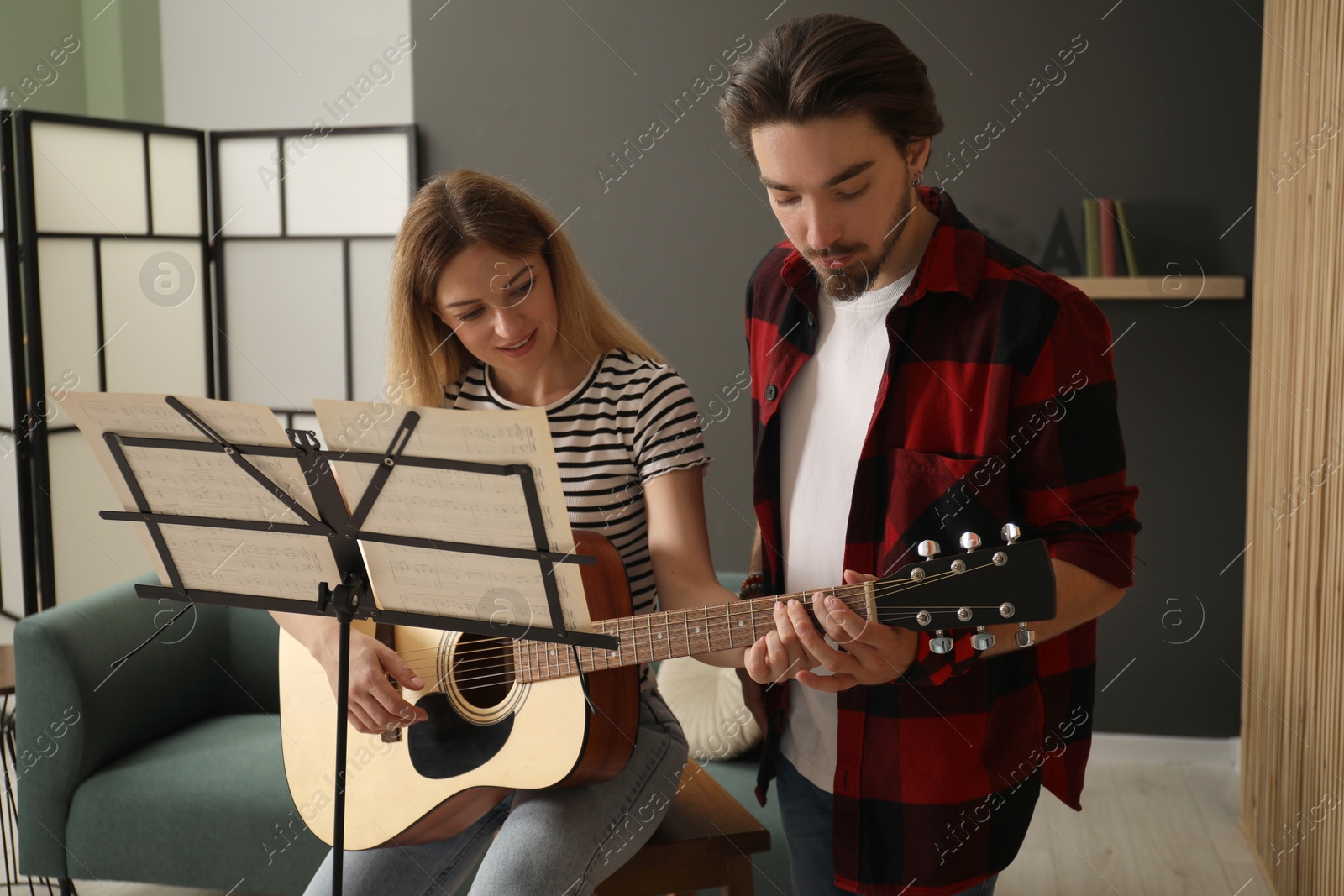 Photo of Tutor teaching woman to play guitar indoors
