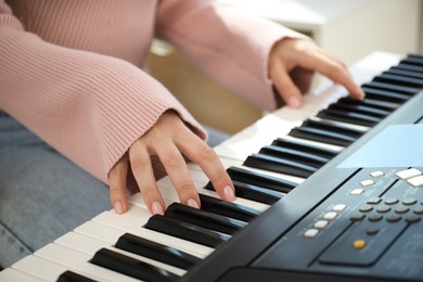 Photo of Woman learning to play piano indoors, closeup