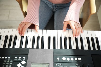 Photo of Woman learning to play piano indoors, closeup