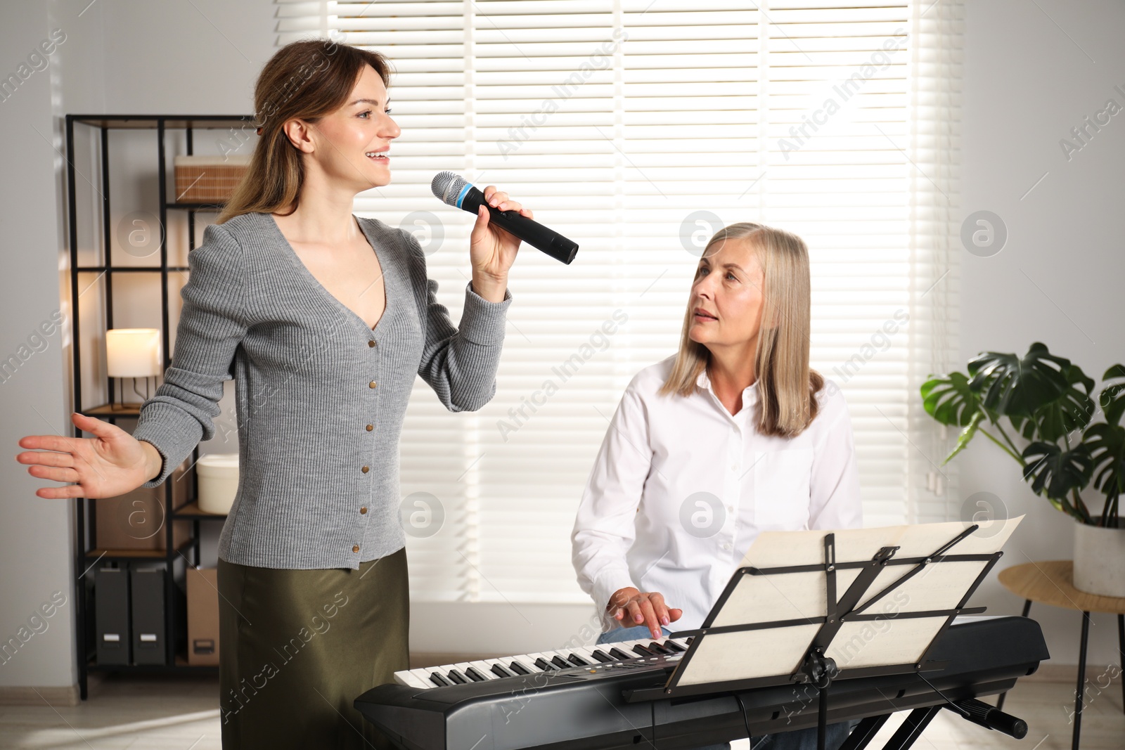Photo of Woman learning to sing while her teacher accompanying on piano indoors