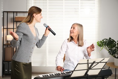 Photo of Woman learning to sing while her teacher accompanying on piano indoors