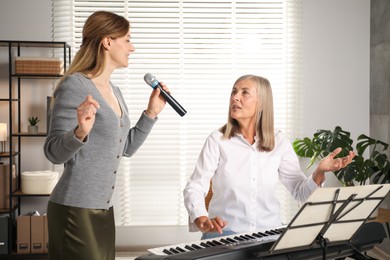 Photo of Woman learning to sing while her teacher accompanying on piano indoors