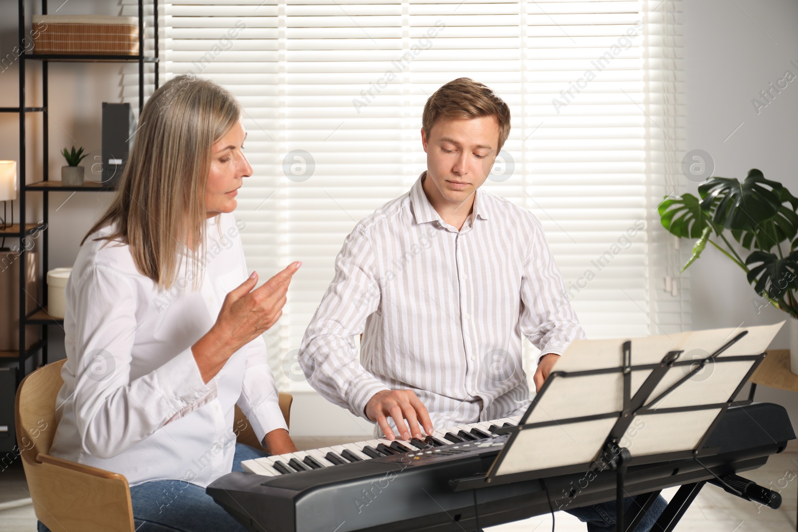 Photo of Tutor teaching man to play piano indoors