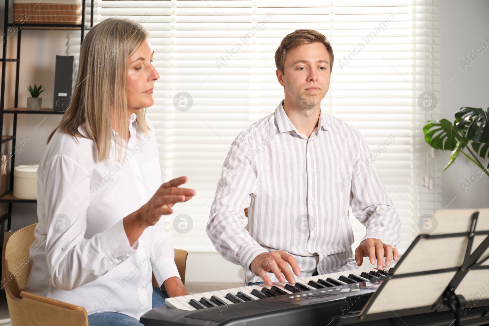 Photo of Tutor teaching man to play piano indoors