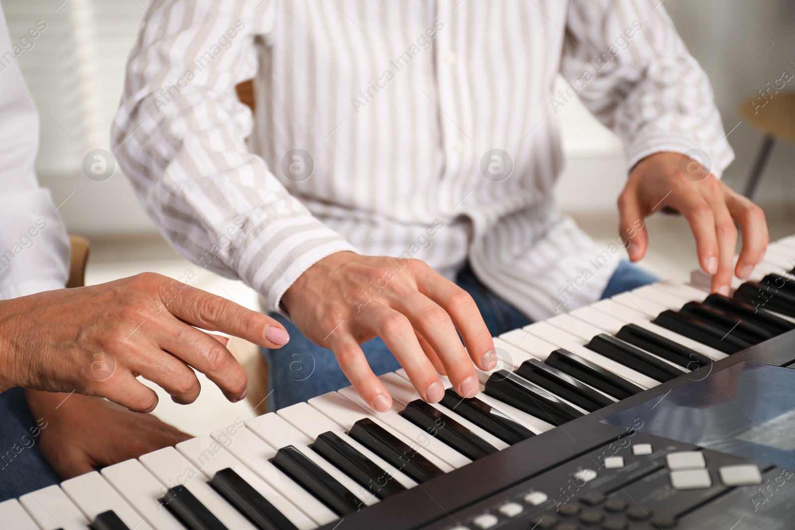 Photo of Tutor teaching man to play piano indoors, closeup