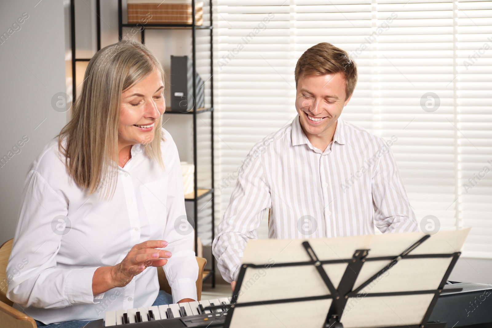 Photo of Tutor teaching man to play piano indoors