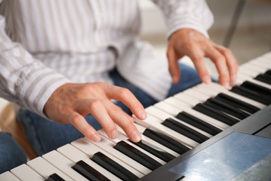 Photo of Man learning to play piano indoors, closeup