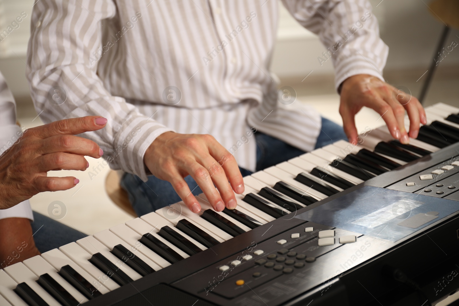 Photo of Tutor teaching man to play piano indoors, closeup