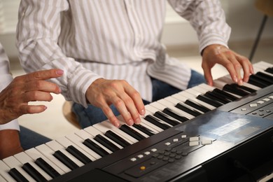 Photo of Tutor teaching man to play piano indoors, closeup