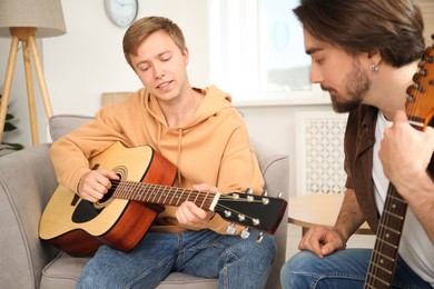 Photo of Tutor teaching man to play guitar at home