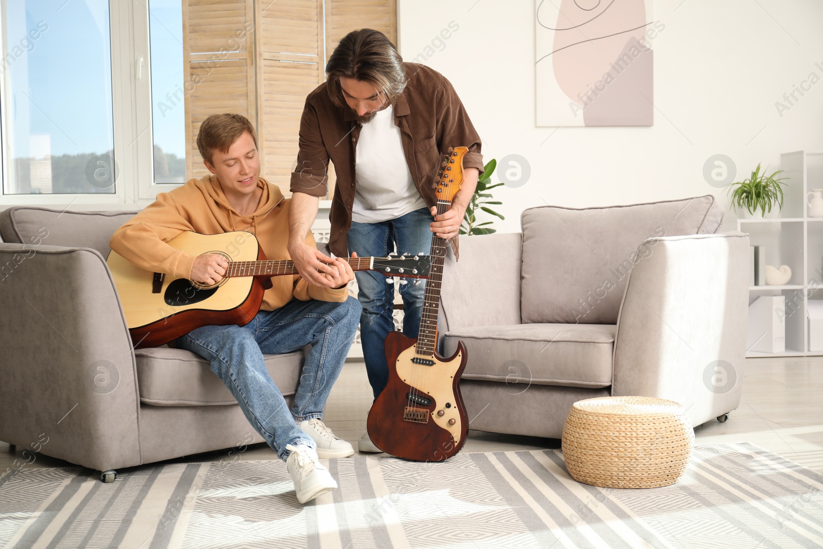 Photo of Tutor teaching man to play guitar at home