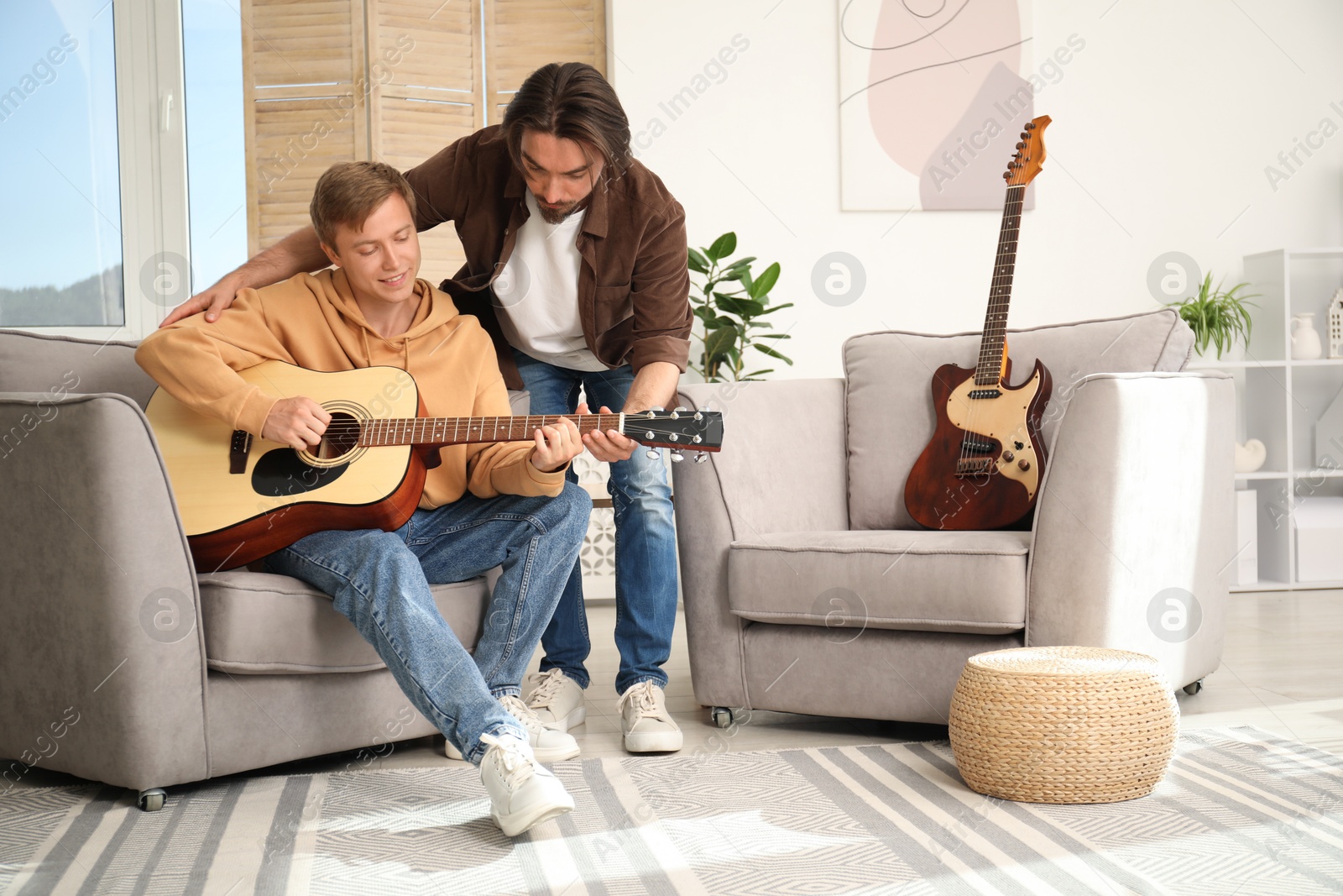 Photo of Tutor teaching man to play guitar at home