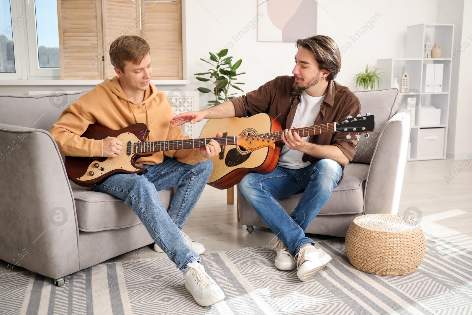 Photo of Tutor teaching man to play guitar at home