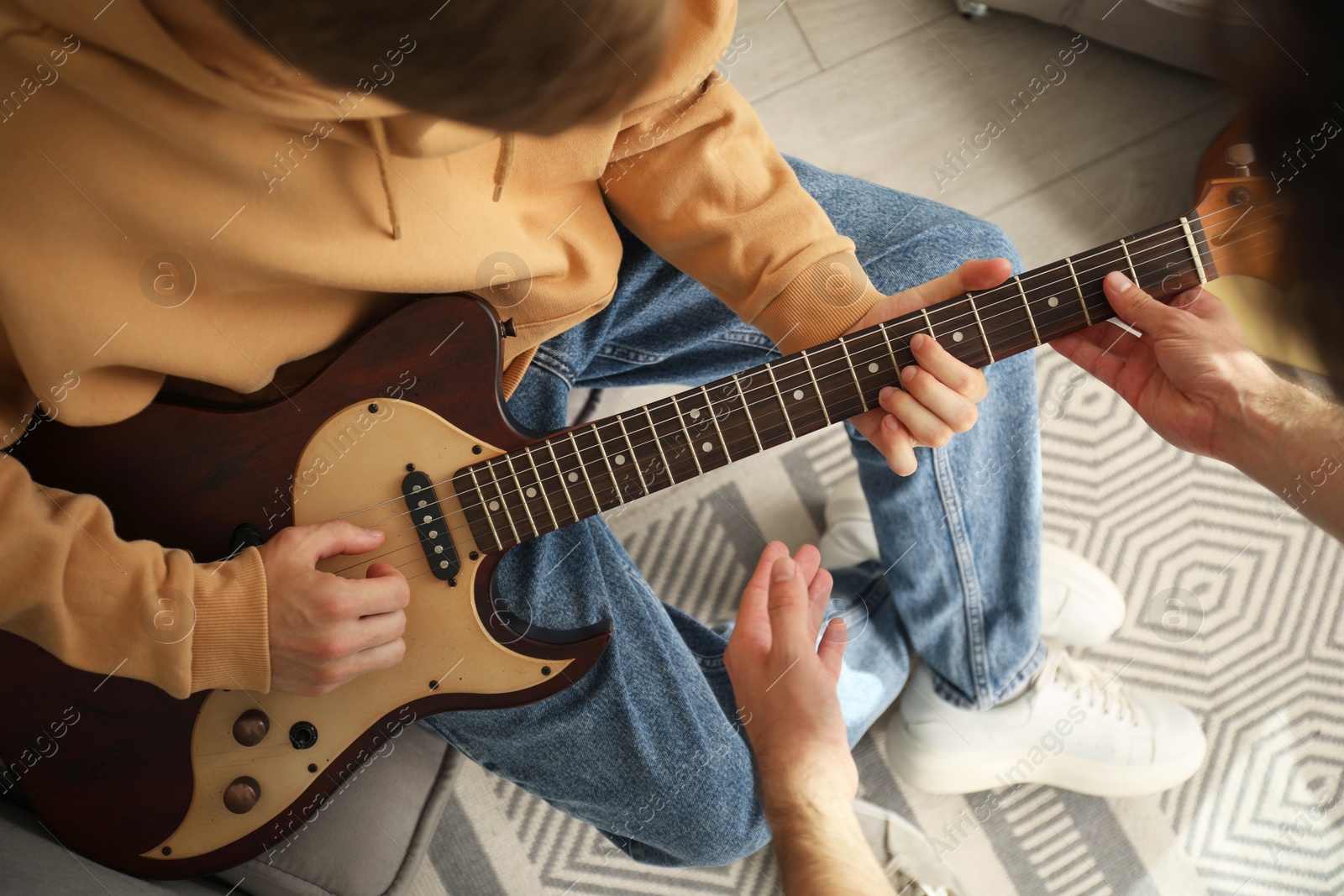 Photo of Tutor teaching man to play guitar at home, closeup