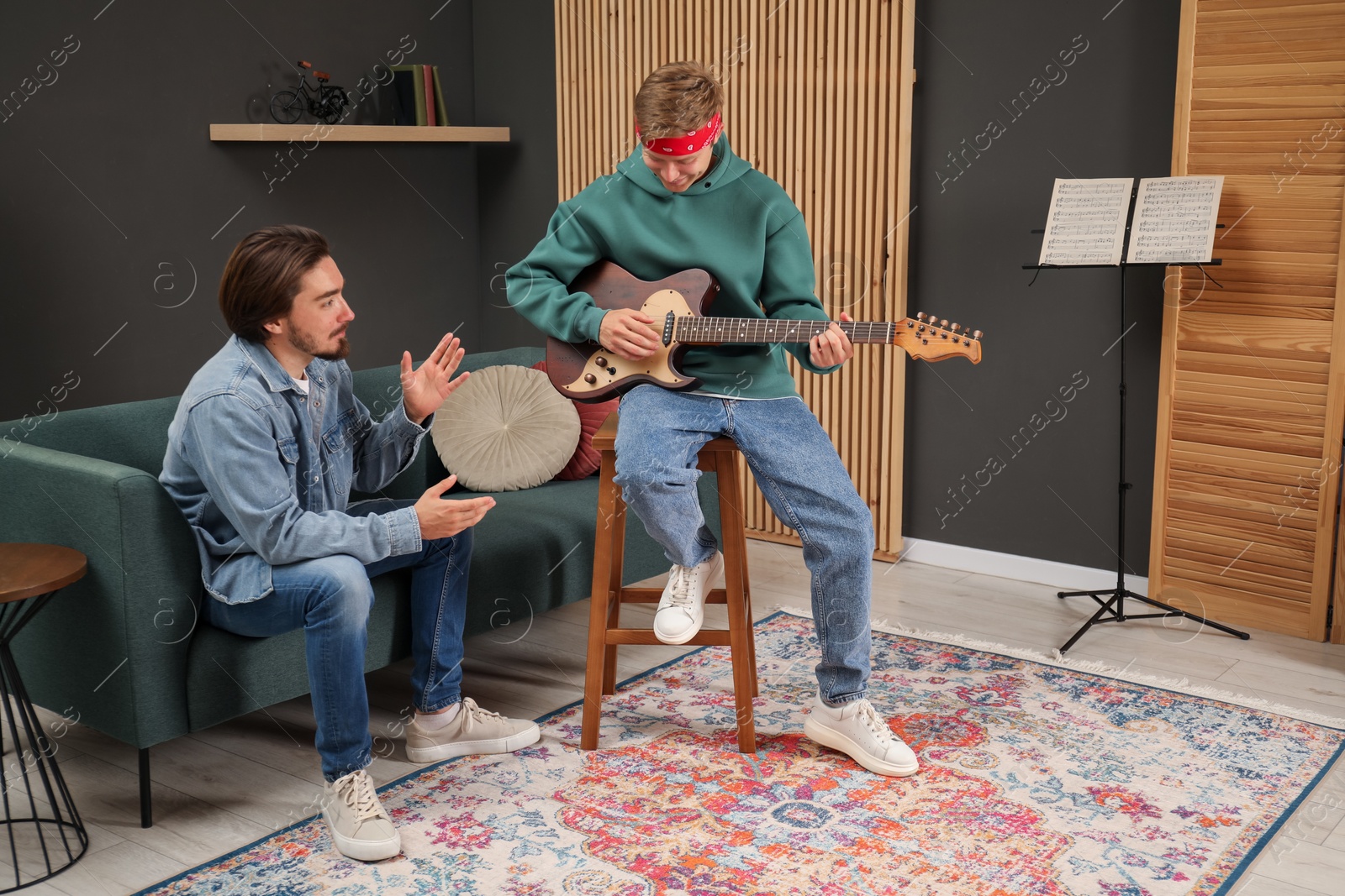 Photo of Tutor teaching man to play guitar indoors