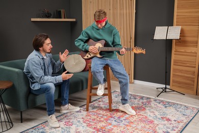 Photo of Tutor teaching man to play guitar indoors