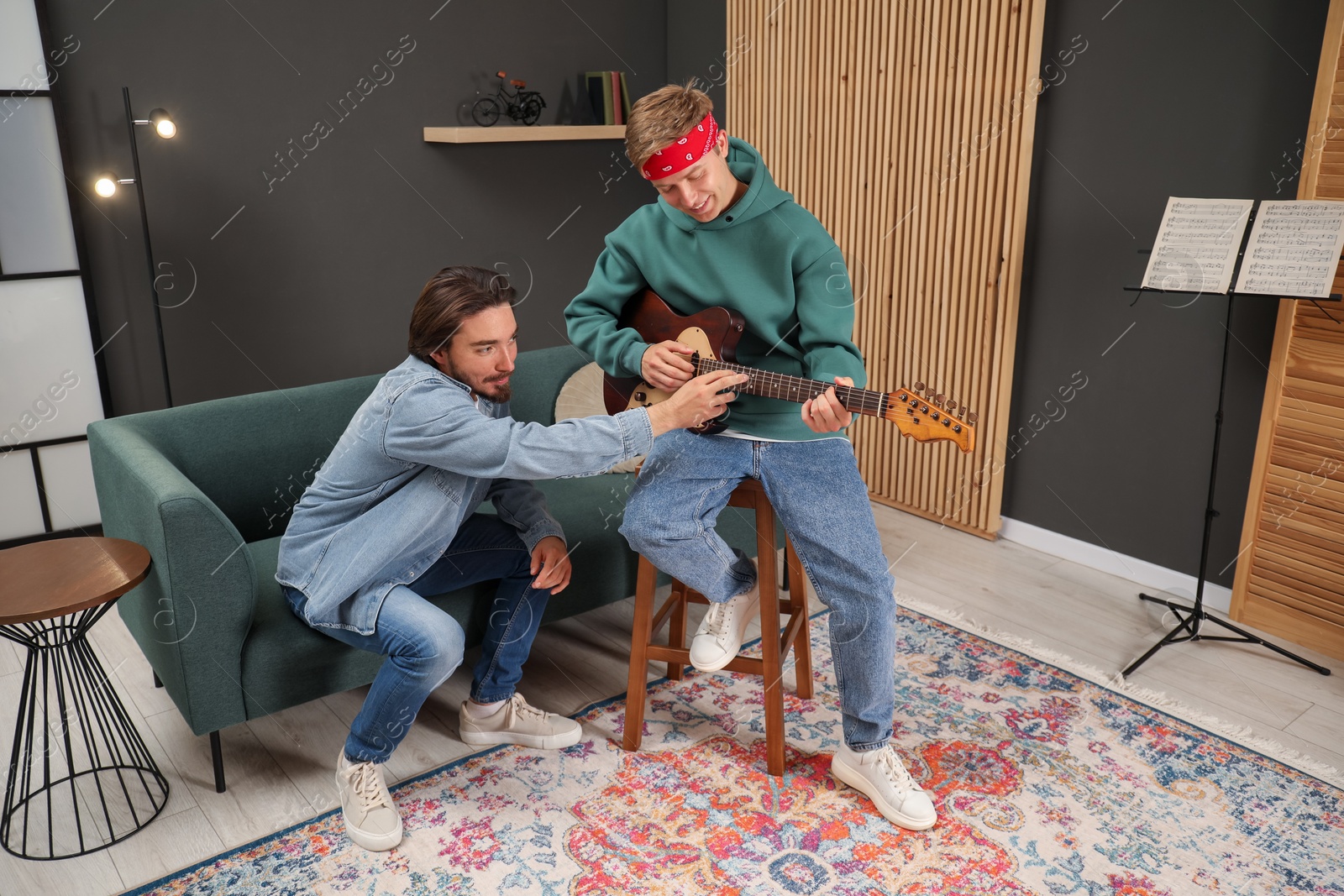 Photo of Tutor teaching man to play guitar indoors