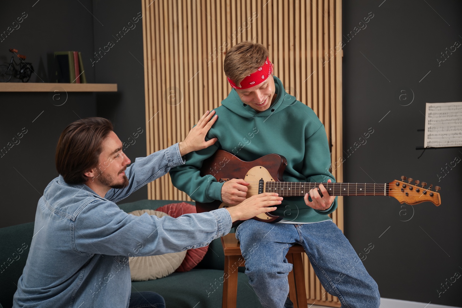 Photo of Tutor teaching man to play guitar indoors