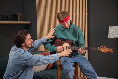 Photo of Tutor teaching man to play guitar indoors