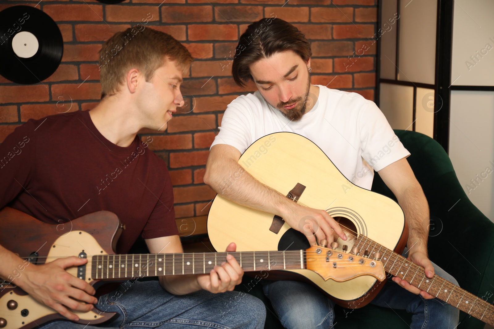 Photo of Tutor teaching man to play guitar indoors