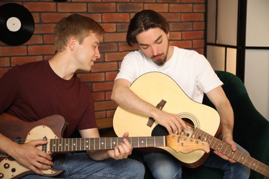Photo of Tutor teaching man to play guitar indoors