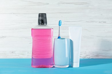 Photo of Mouthwash, toothpaste and toothbrush on blue wooden table against white background. Oral hygiene