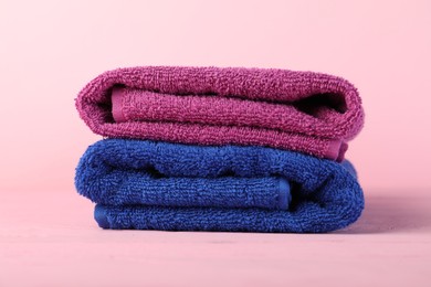 Photo of Colorful fresh terry towels on pink wooden table, closeup
