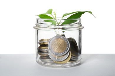 Photo of Glass jar with money and sprout isolated on white