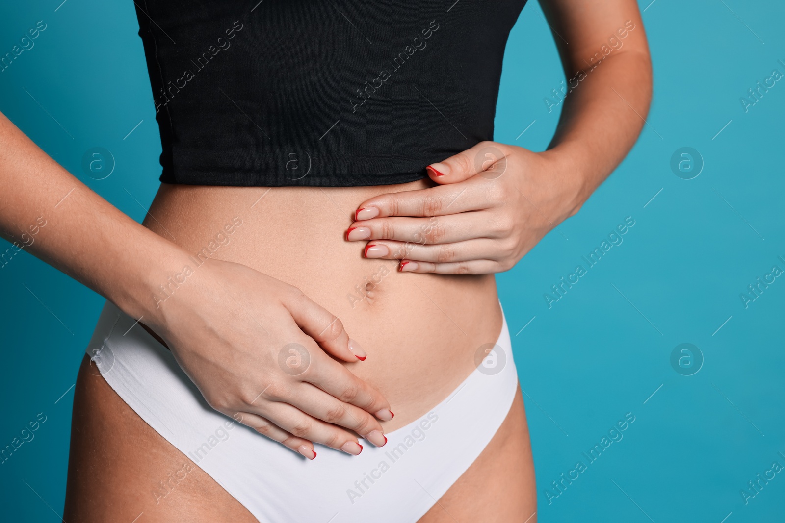 Photo of Young woman with flat belly on light blue background, closeup