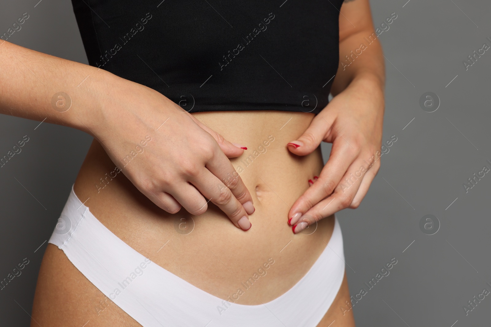 Photo of Young woman with flat belly on grey background, closeup