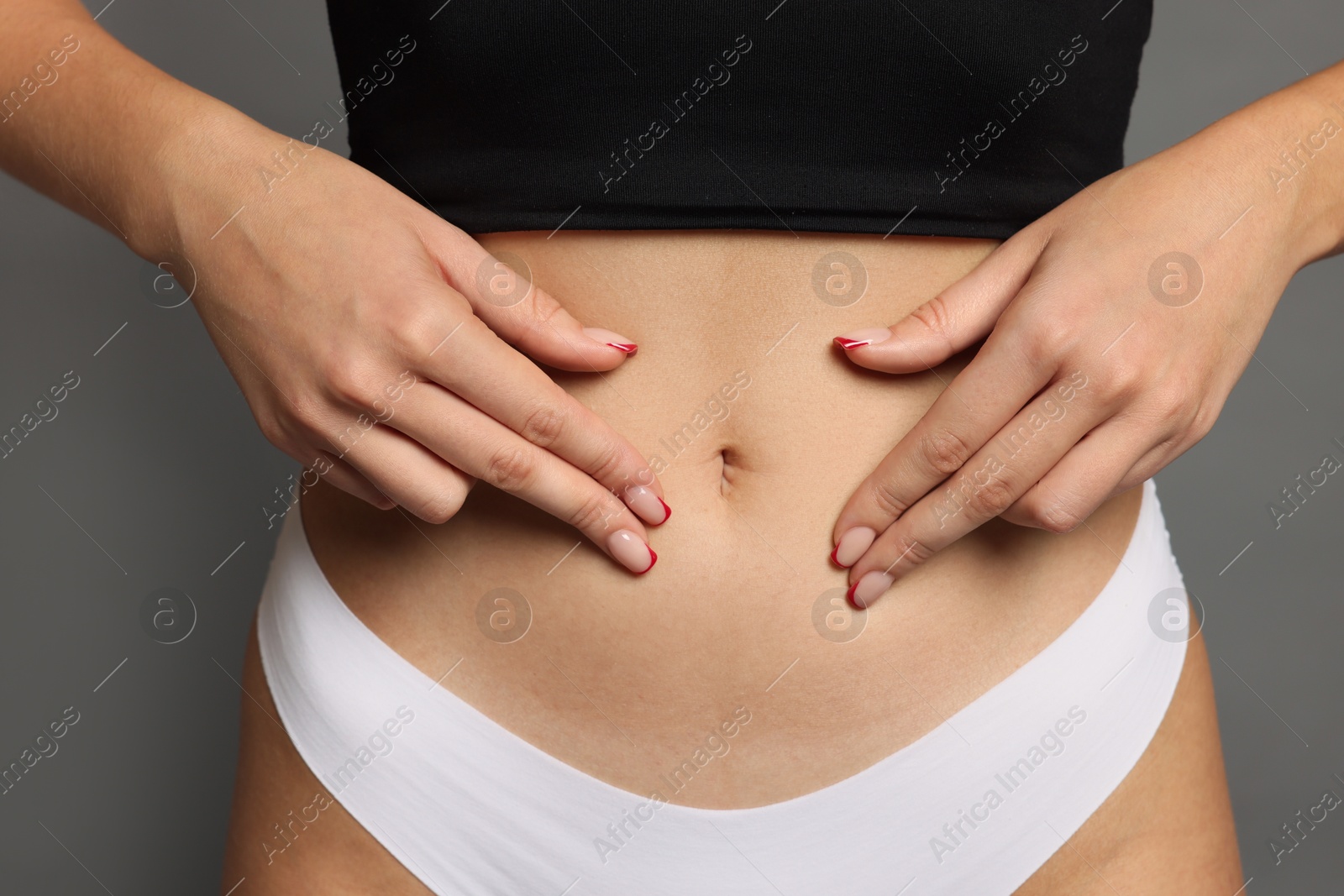 Photo of Young woman with flat belly on grey background, closeup