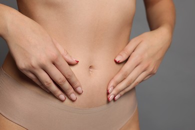 Photo of Young woman with flat belly on grey background, closeup