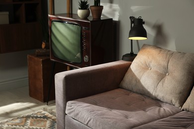 Photo of Soft sofa, retro TV set and other used stuff indoors