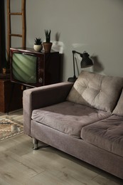 Photo of Soft sofa, retro TV set and other used stuff indoors