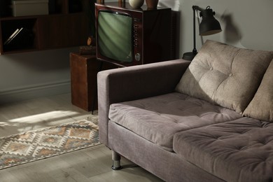 Photo of Soft sofa, retro TV set and other used stuff indoors