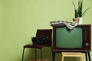 Photo of Retro TV set and other used stuff on olive background